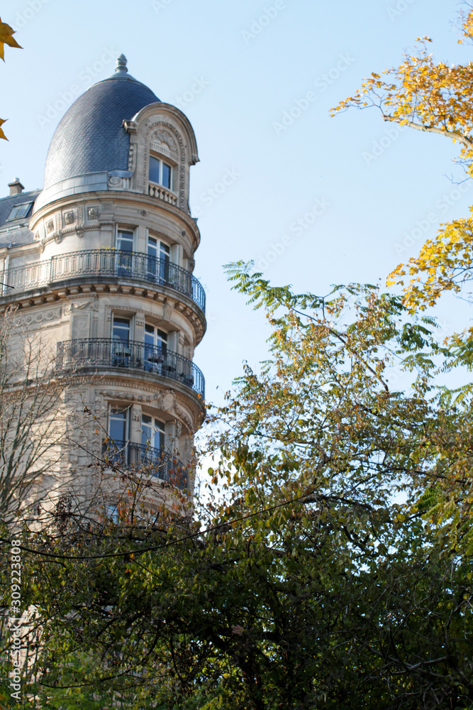 Fototapeta premium Foliage view over Paris Haussmann round facade with traditional balconies