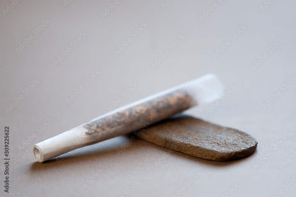 Medical Hashish in the Kingdom of Morocco - CBD medical Moroccan cannabis hashish, with prepared cigar, tobacco pack, book and headphones in the background Medical Hashish in the Kingdom of Morocco - CBD medical Moroccan cannabis hashish, with prepared cigar, tobacco pack, book and headphones in the background