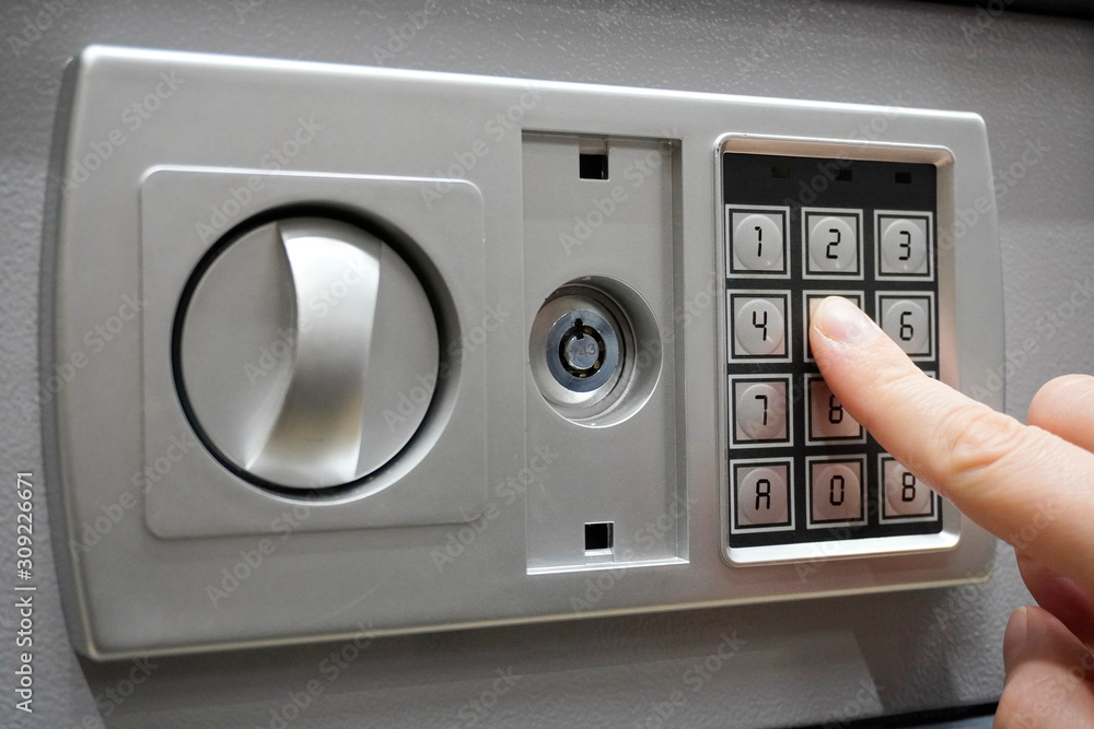 the man dials the code to close the safe. Grey safe closure, numeric keypad. A man presses the keys on the digital panel on the safe. the man dials the code to close the safe. Grey safe closure, numeric keypad. A man presses the keys on the digital panel on the safe.