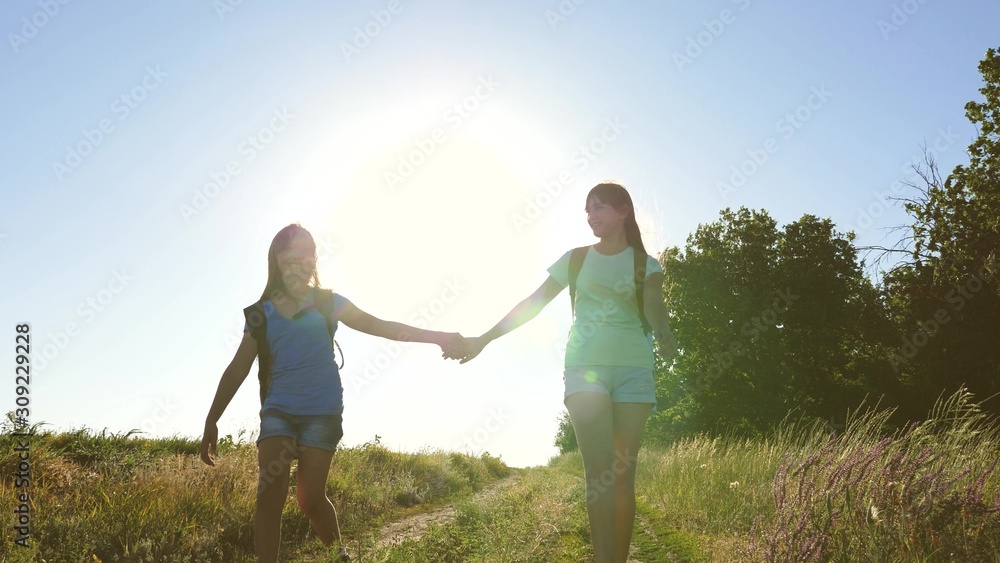 teamwork tourists teenagers. Woman travelers walk on road in the countryside. happy hiker girl in summer park. Happy girls travelers go with backpacks in field. teenager girl adventures on vacation.