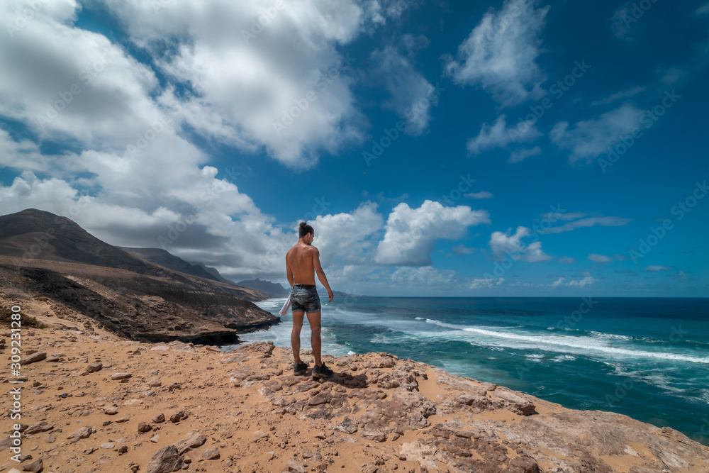 Hombre joven llega al final del camino despues de atravesar las dunas y contempla el paisaje. Hombre joven llega al final del camino despues de atravesar las dunas y contempla el paisaje.
