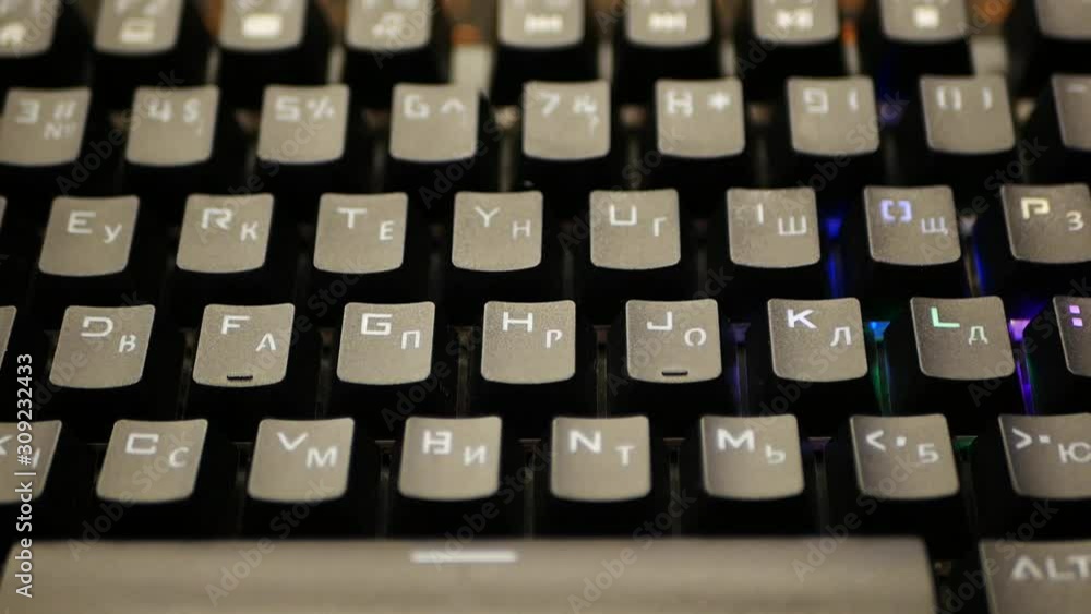 Multi-colored keyboard. The keyboard backlight shimmers in different colors. Wiring towards the camera. RGB keyboard. close-up. View from the face. Hacker. typing on a modern trendy keyboard. Cybercri Multi-colored keyboard. The keyboard backlight shimmers in different colors. Wiring towards the camera. RGB keyboard. close-up. View from the face. Hacker. typing on a modern trendy keyboard. Cybercri
