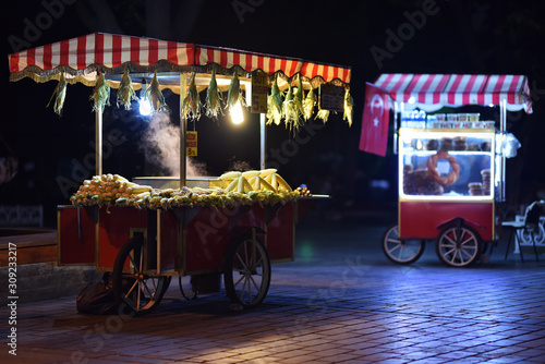 Traditional carts of Turkish street food in night. Text on signboards in translation from Turkish language on English is Roasted chestnuts and corn. photo