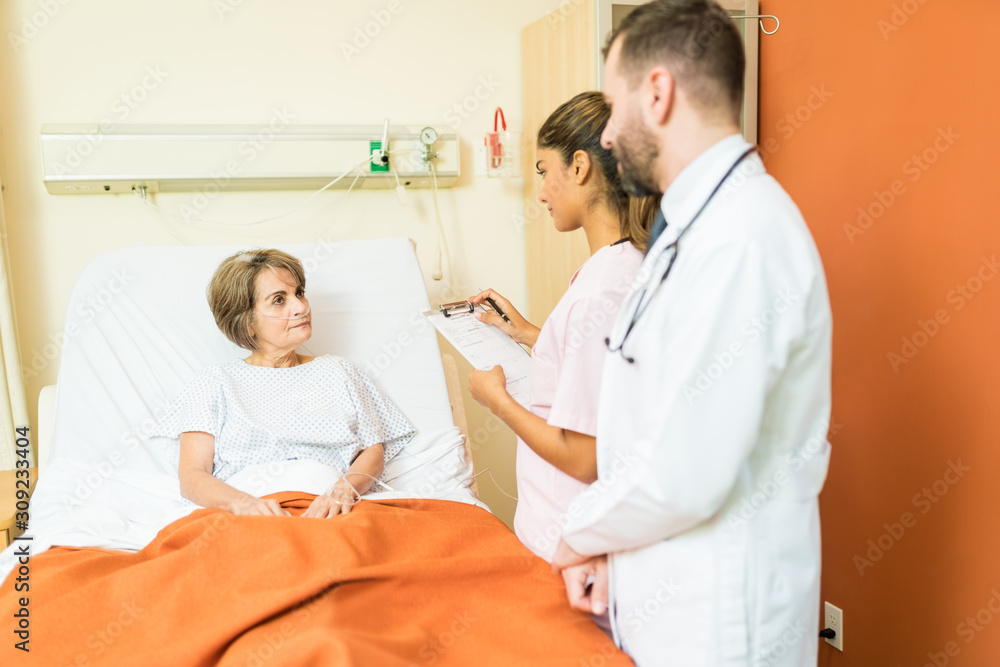 Hispanic Doctors Discussing With Patient At Hospital Hispanic Doctors Discussing With Patient At Hospital
