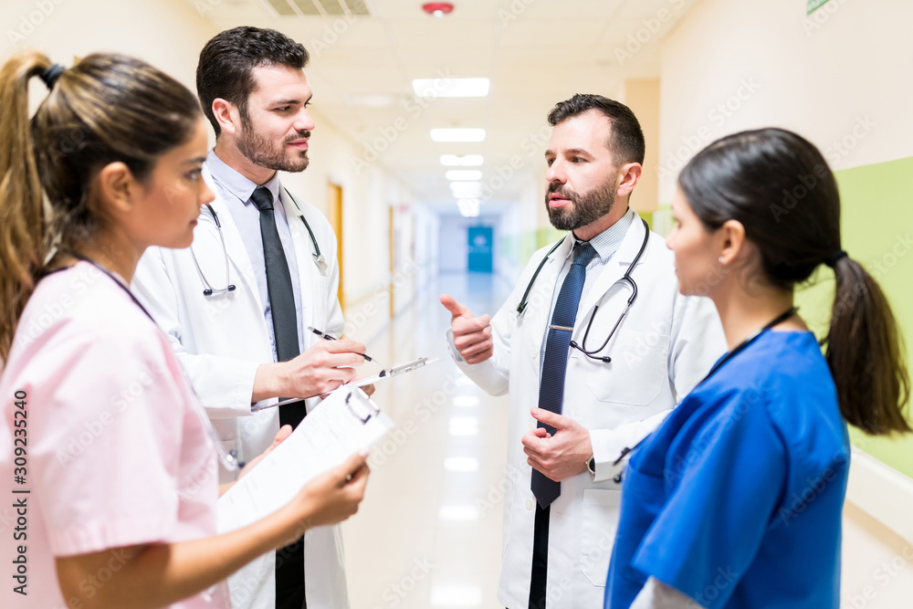 Medical Professionals Discussing In Hospital Corridor Medical Professionals Discussing In Hospital Corridor