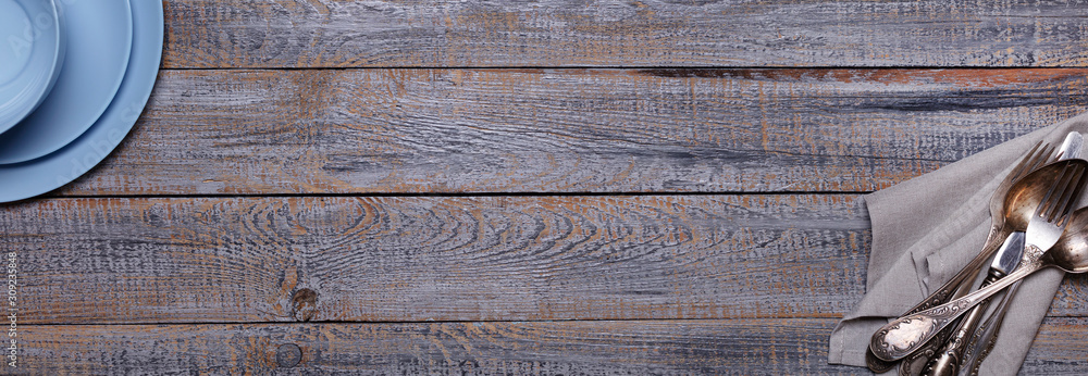 Blue plates, napkin and cutlery on an old gray wooden background. Blue plates, napkin and cutlery on an old gray wooden background.