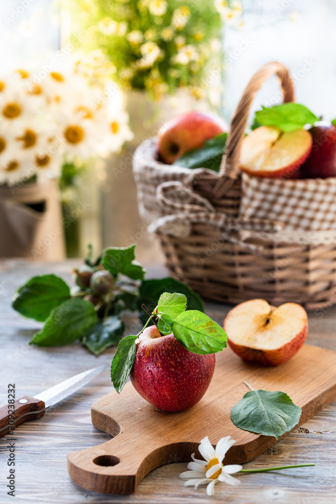 Homemade compote of summer apples on a wooden table by the window. Basket of apples. Wild flowers of the chamomile in the jar Homemade compote of summer apples on a wooden table by the window. Basket of apples. Wild flowers of the chamomile in the jar