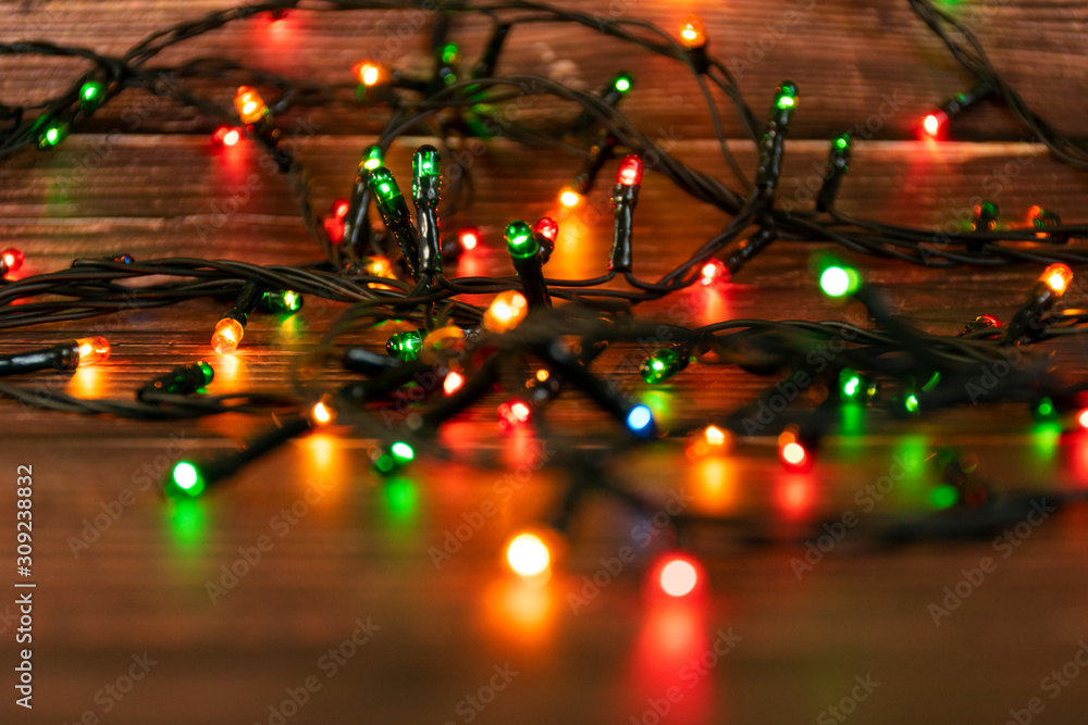 Colorful christmas garland lights on brown wooden background. Christmas Light with Copyspace for New Year Frame or Christmas Layout. Christmas decorations showcases