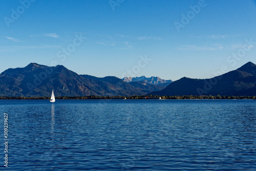 Landschaft am Chiemsee mit Segelboot und den Alpen im Hintergrund