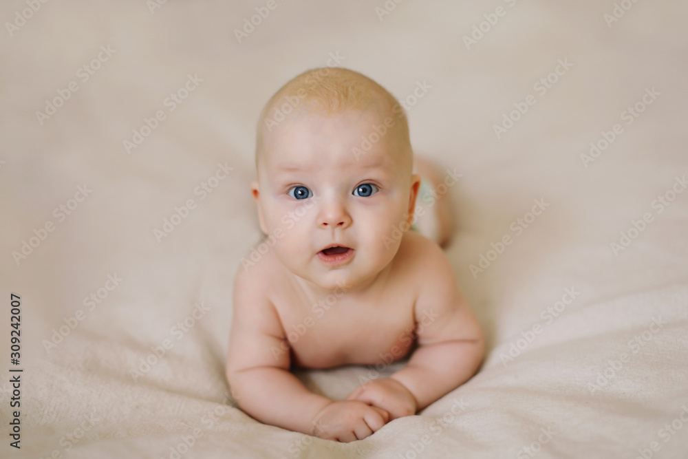Funny little baby lying on a white knitted blanket. Child nappy change and skin care. 