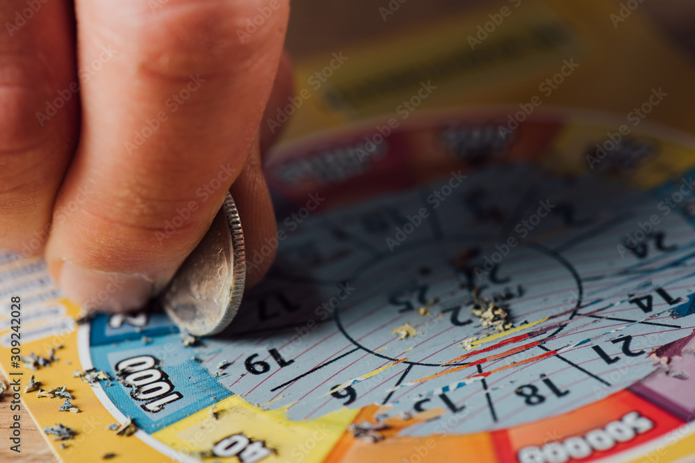 Obraz premium cropped view of gambler scratching lottery ticket with silver coin
