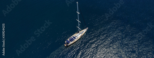 Aerial drone top down ultra wide photo of luxury sail boat with wooden deck docked in Aegean deep blue sea  © aerial-drone