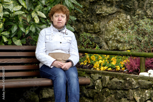 Spring. Russian woman in Rivo Del Gardo sitting on a bench photo