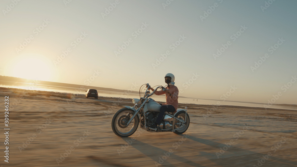 Fototapeta premium Motorcyclist driving his motorcycle on the dirt road during sunset