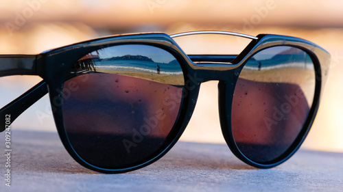 Reflection of a tropical beach in a stylish sunglasses. Selective focus