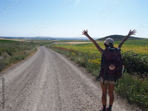 Pilgrim with raised arms on the road to Santiago de Compostela, Camino de Santiago, Way of St. James,  Journey from Castrojeriz to Poblacion de Campos, French way, Spain