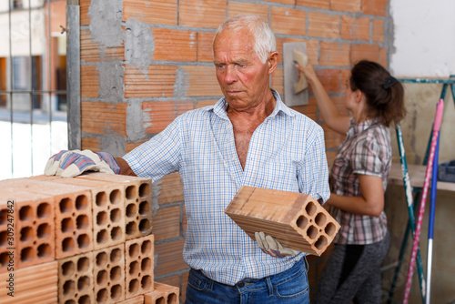 Man with woman installing brick wall