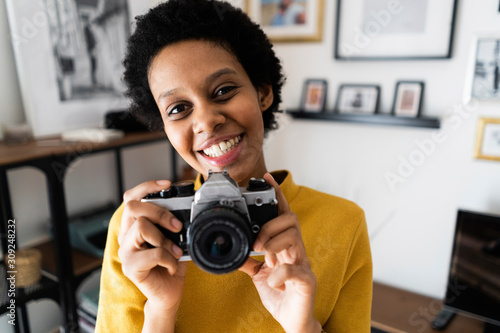 Portait of smiling young woman with vintage camera at home photo