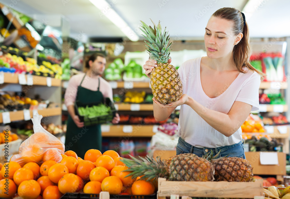 Adult woman customer holding fresh pineapple