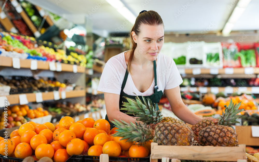 Young woman wearing apron working with fresh pineapples