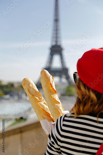 Woman standing with baguettes in Paris. Eiffel Tower in the background. French theme and vibes.  photo