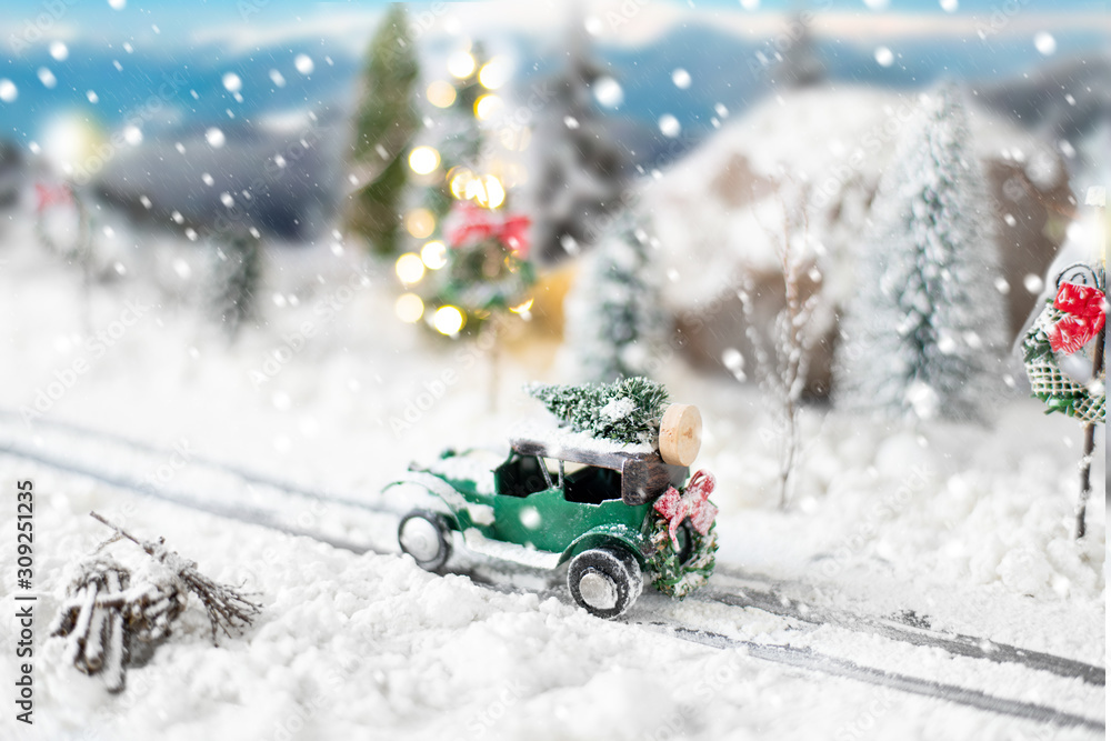 Miniature classic car carrying a christmas tree on snowy winter landscape Miniature classic car carrying a christmas tree on snowy winter landscape
