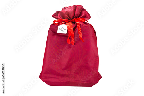 A Christmas gift wrapped in a burgundy fabric with a ribbon, with the inscription "a gift for you" on a piece of paper, isolated on a white background with a clipping path.