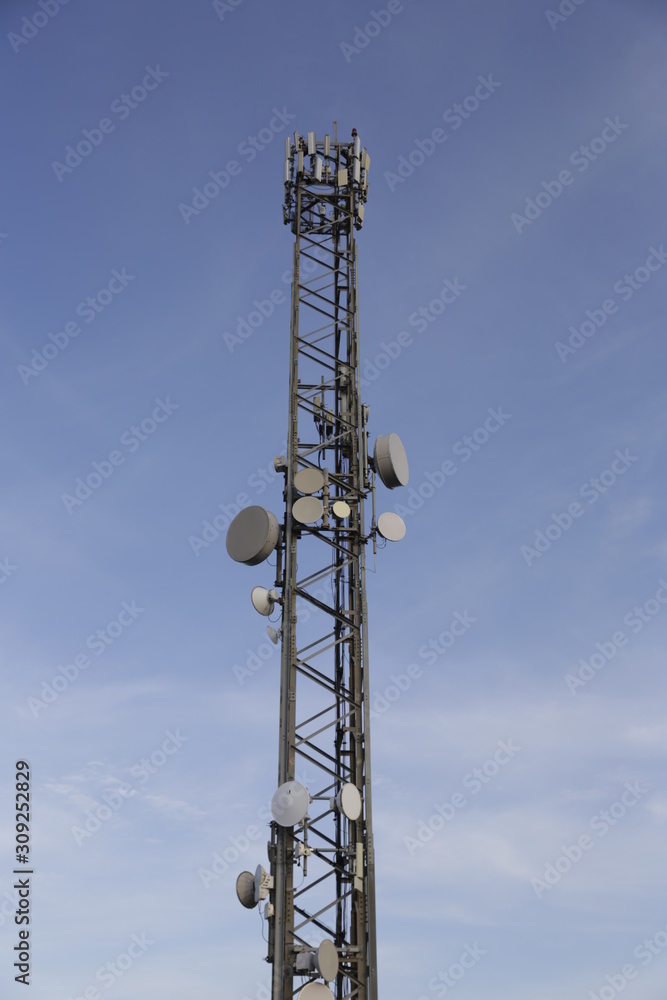Telecommunications tower, antenna and satellite dish with blue sky at the top of the hill. Communication theme. Wireless technology. Telecommunications tower, antenna and satellite dish with blue sky at the top of the hill. Communication theme. Wireless technology.