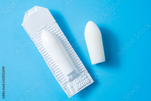 White suppositories for anal or vaginal use on blue background. Medical candles for treatment of Candida, thrush, hemorrhoids, inflammation and fever. Effective drug for timely treatment of diseases