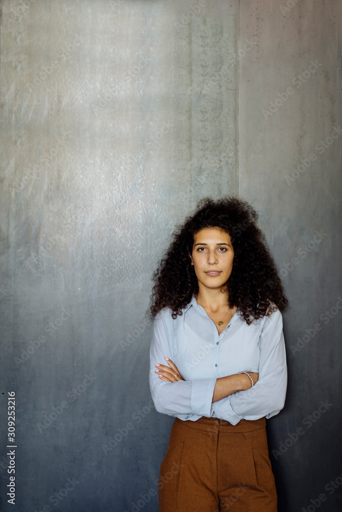 Portrait of a confident young businesswoman standing in front of a grey wall Portrait of a confident young businesswoman standing in front of a grey wall