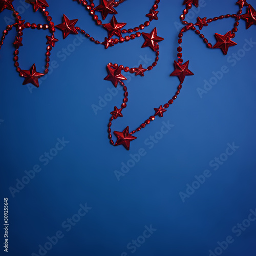 Red Christmas beads with stars on a blue background. Color of the year 2020, Classic Blue