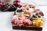 Antipasto platter with ham, prosciutto, salami, cheese,  crackers and olives on a light background.  Christmas table.