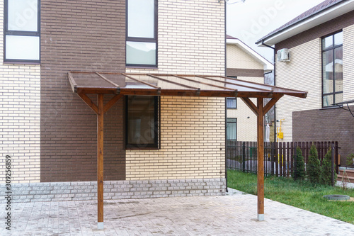 Wooden carport with a transparent roof made of tinted plastic.