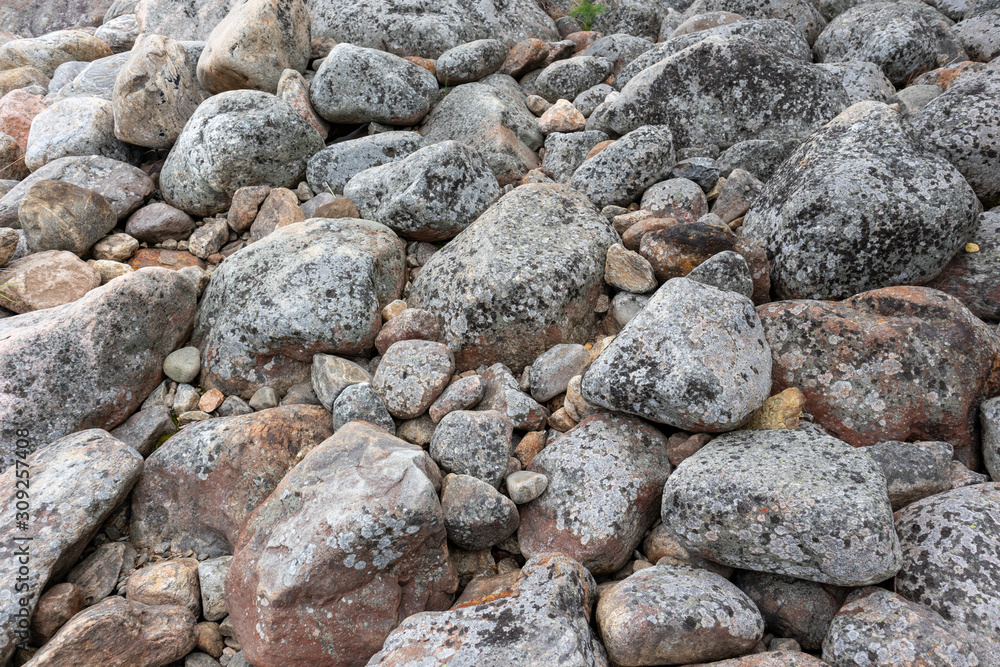 Grey granite stones on natural northern seashore. Close up gray texture, rough surface material. For design, web