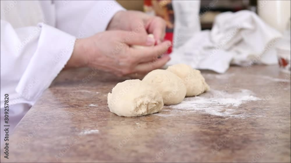 Chef shaping small dough pieces into rolls on the kitchen counter. Chef shaping small dough pieces into rolls on the kitchen counter.