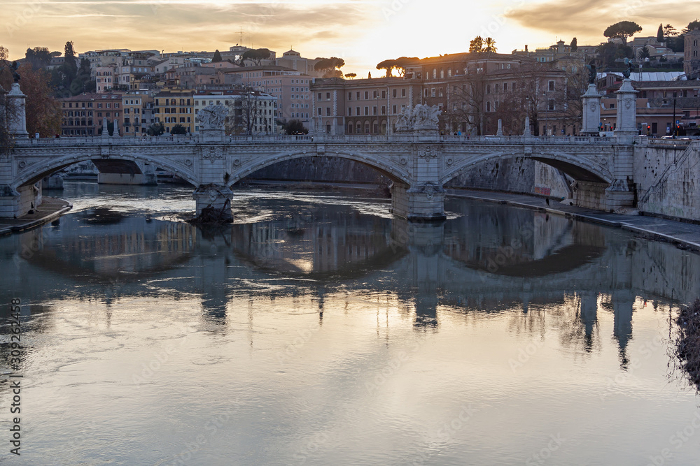 Ancient bridge through the Tiber River in Rome on sunset background, Italy