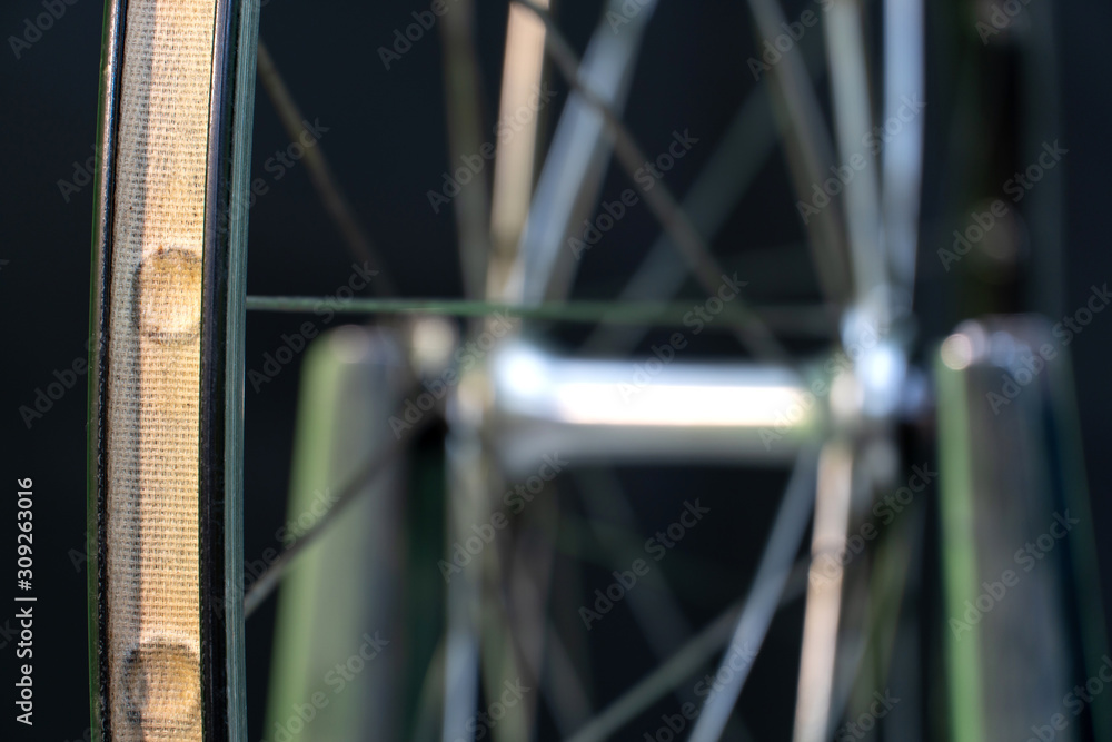 Bicycle repair. The front wheel is on a stand on a black background. Rim and spokes close-up. Mechanic levels the wheel in the workshop. wheel truing stand