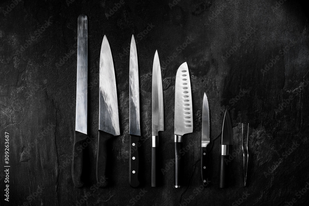 Set of professional kitchen knives and tweezers on dark stone background. Creative layout. Chef, restaurant or kitchen concept. Top view, copy space