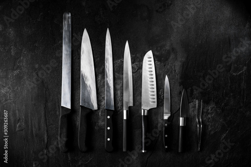 Obraz na płótnie Set of professional kitchen knives and tweezers on dark stone background. Creative layout. Chef, restaurant or kitchen concept. Top view, copy space w salonie