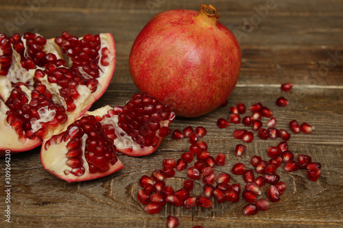 fresh pomegranate and sliced ​​pomegranate with red seeds on a wooden table. Healthy fruits, vegan food, diet.