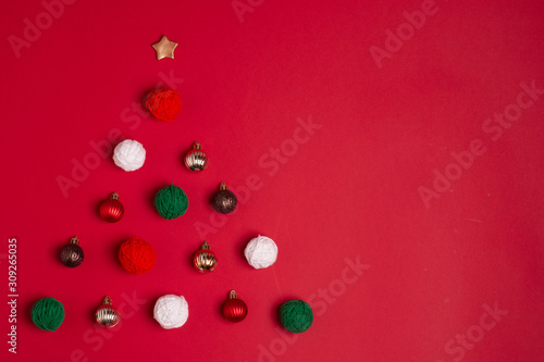 Creative christmas tree made of New years balls and on the red background. © Ирина Кузьменко
