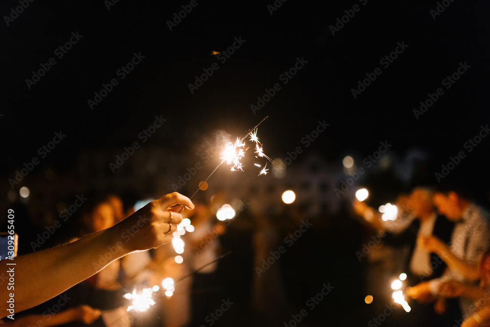 Sparklers in hands in night close up