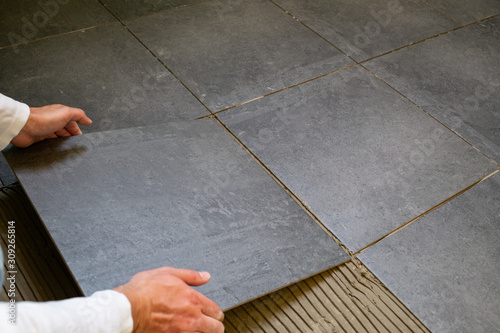 Tiler installing ceramic tiles on a floor