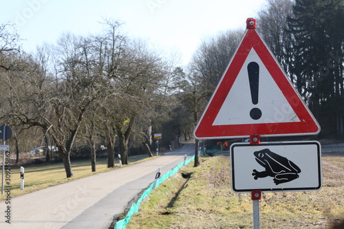 A lonely road in Bavaria with a warning sign at the side telling people about frogs crossing at night