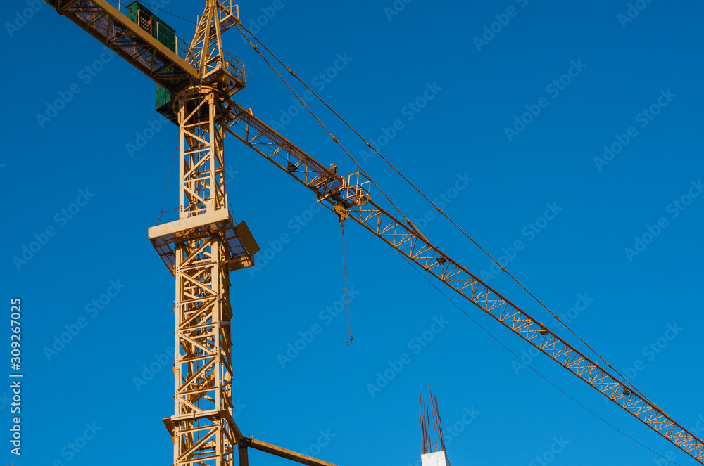 Tower crane against blue sky on a construction site for building of multi storage building or another type of structure. Tower crane against blue sky on a construction site for building of multi storage building or another type of structure.
