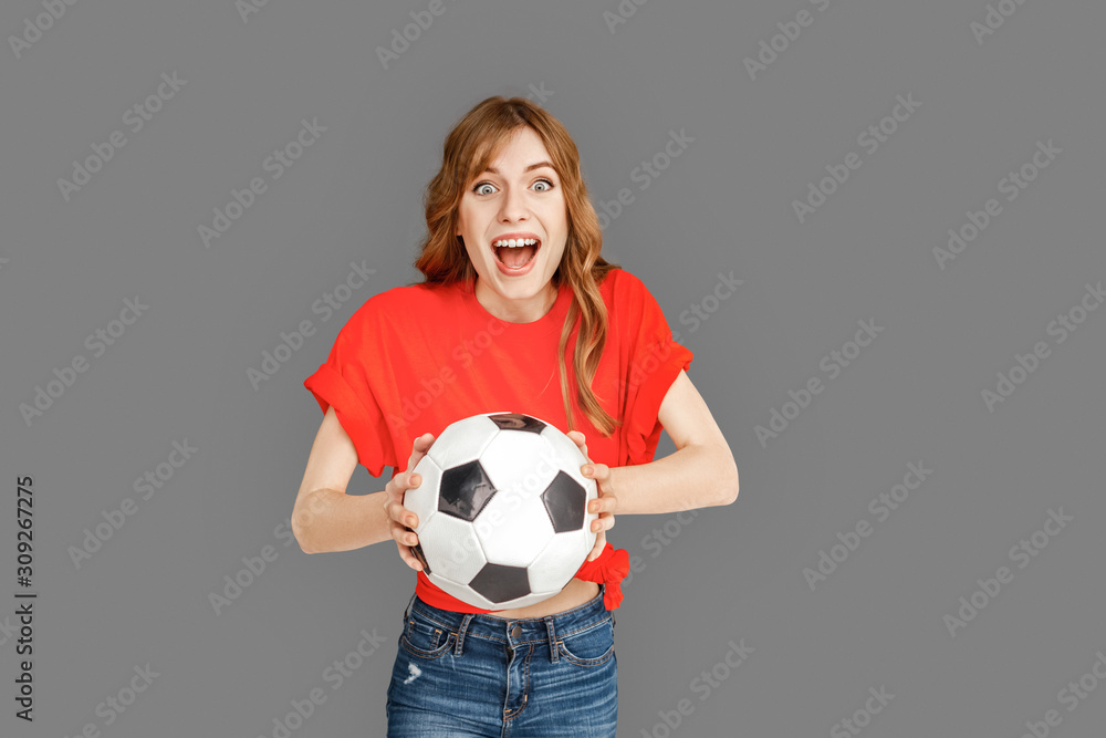 Freestyle. Woman in sports clothes studio standing isolated on grey with ball smiling cheerful