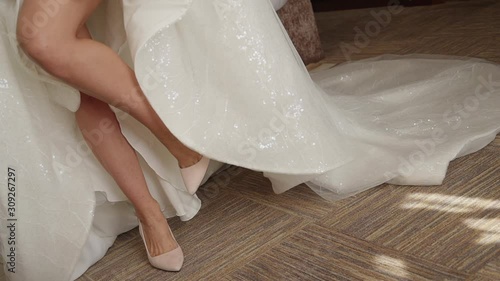 bride in white dress and heels. closeup of woman legs and feet. female lifting her leg. elegant slim bridal foot. concept symbol, attractive, shoe. fitting clothing gown preparing for wedding