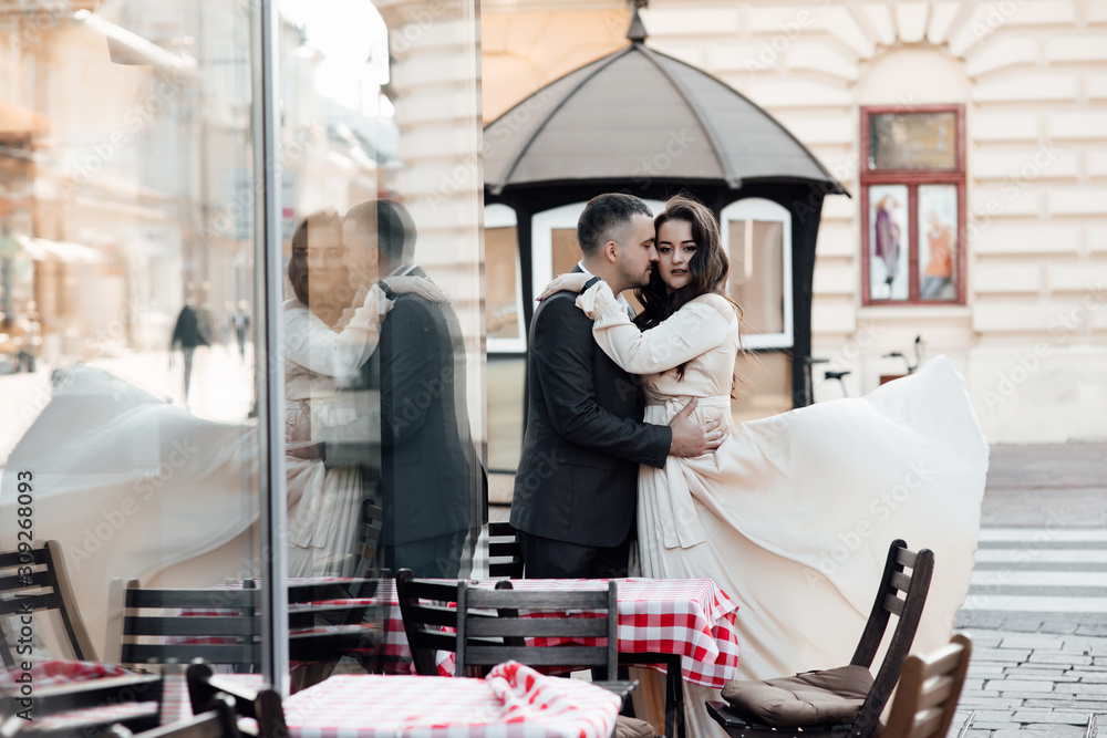 Young couple in good mood sits on the terrace in morning. Pretty woman and handsome man in love. Real love. Happy lovers and family. Happy girl in dress flying in the wind and guy posing in suit.