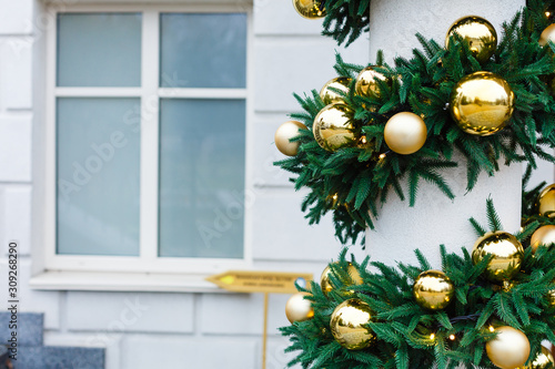 Christmas decorations on the street. A traditional Christmas wreath decorates the columns of the building.
