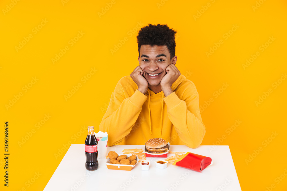 Happy african teenager boy eating fast food meal Happy african teenager boy eating fast food meal